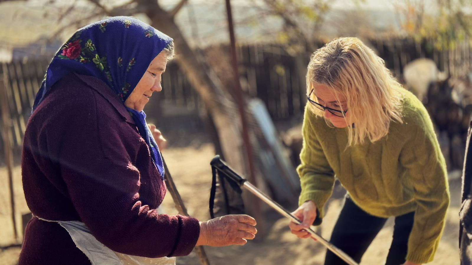 Volunteer supporting elderly woman outdoors